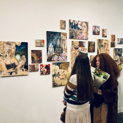 Two women looking at art pieces on a gallery wall