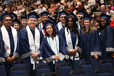 UNF students in caps and gowns smiling at fall 2024 commencement