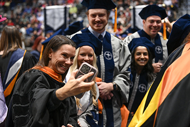 UNF grads posing with a faculty member at fall 2024 commencement