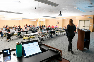 Speaker at the head of a classroom talking to an audience