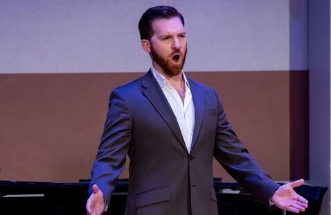 Man in a suit singing on a stage
