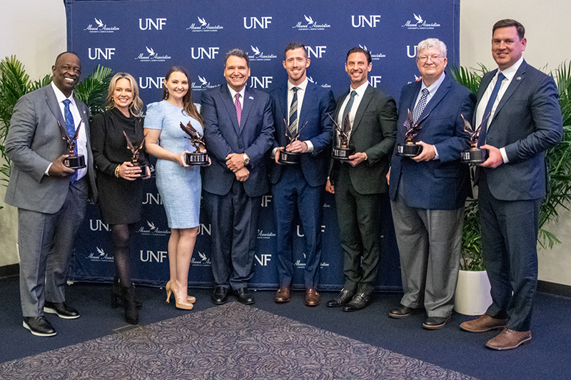 UNF staff and alumni pose for a photo at an alumni event