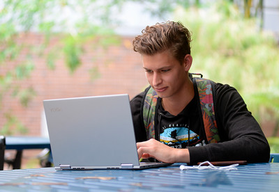 UNF student sitting outside working on his laptop