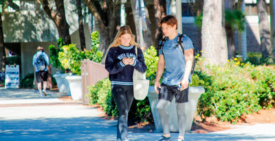 Male and female UNF students walking on a sidewalk together on campus