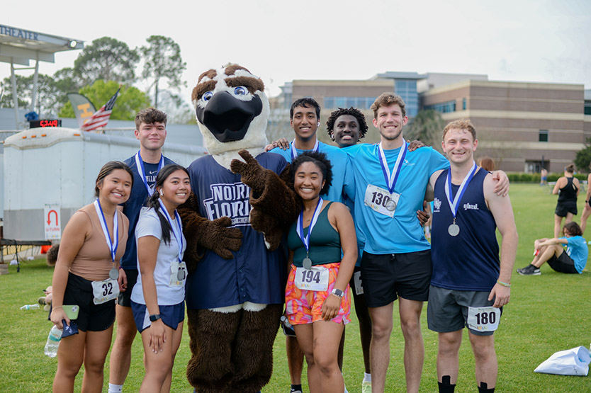 UNF Swoop the Loop 5K Run participants pose for a picture with Ozzie the mascot