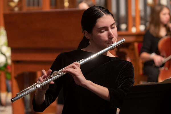 Female musician wearing black playing a flute