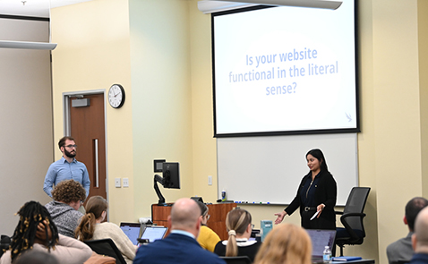 Speaker standing in front of a classroom speaking to an audience