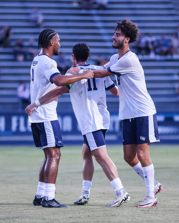 UNF men's soccer player hugging and celebrating on the field