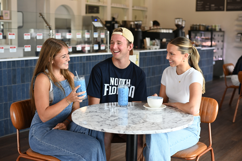 Three UNF students sitting at a coffee shop smiling and having drinks