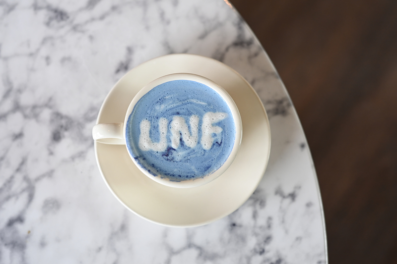 foam drink in a tea cup with the UNF abbreviation spelled in foam