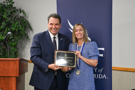 Dr. Heather Barnes Truelove with UNF President Moez Limayem holding an award