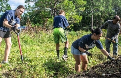 Volunteers with shovels working in a yard