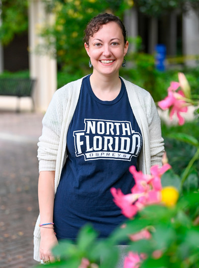 Jennifer Wells smiling while wearing a blue North Florida Ospreys shirt