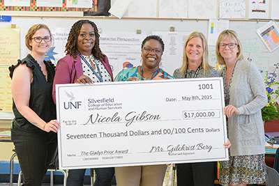 Nicola Gibson holding her check with co-teachers