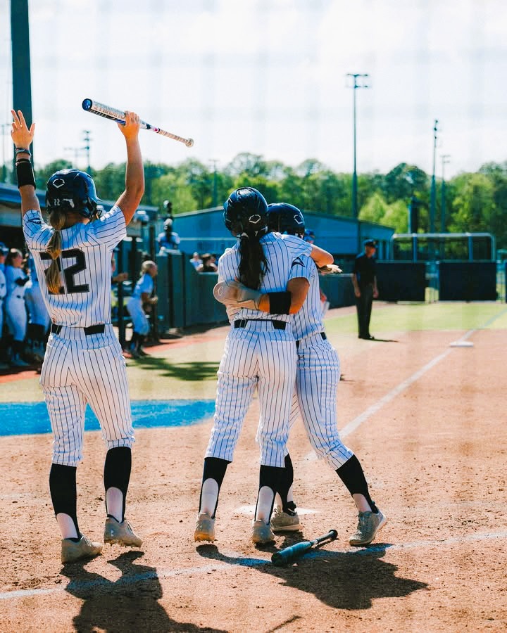 Softball players hugging and cheering on the field