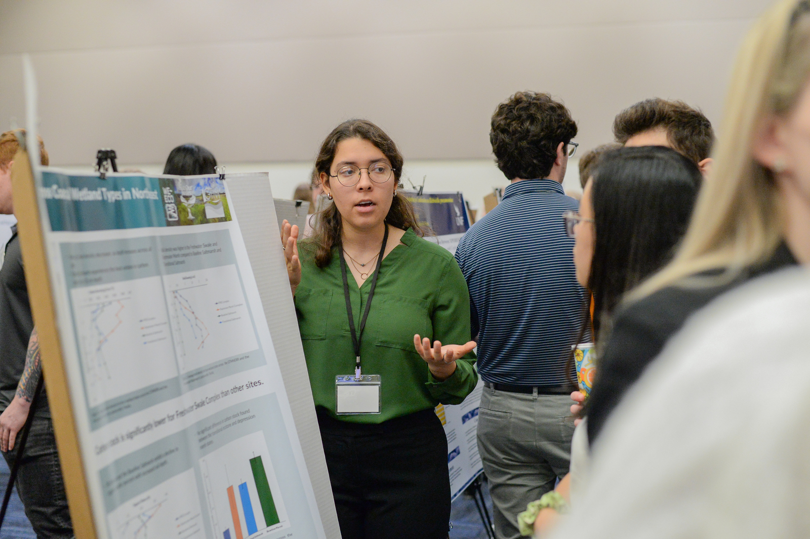 Student standing next to research poster conversing with onlookers