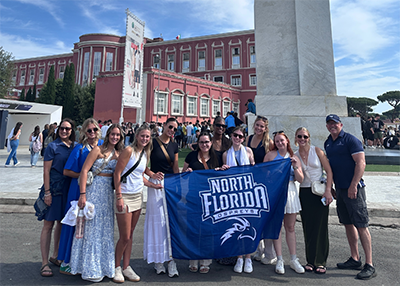 UNF faculty and students on a study abroad trip with UNF flag