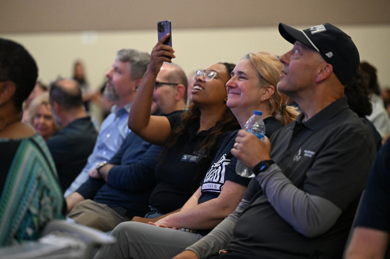UNF employees sitting and cheering at an event