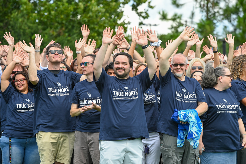 UNF employees gathered with their arms raised