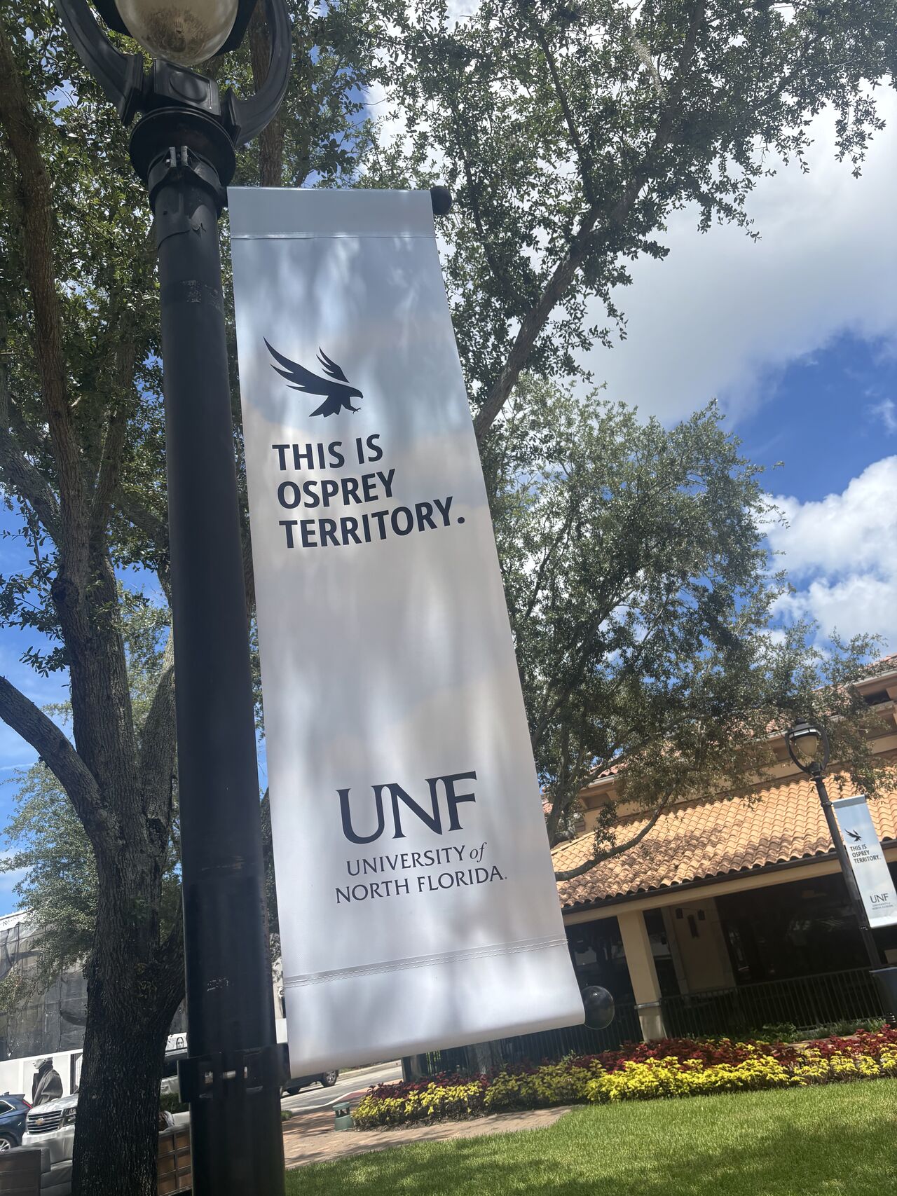 UNF students posing behind UNF brand letter statue