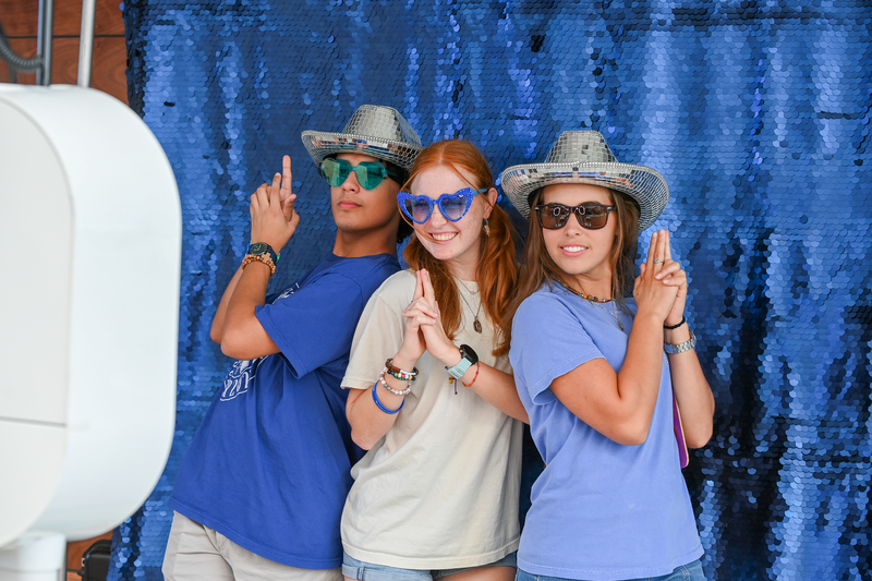 UNF pose in a photobooth wearing miscellaneous accessories