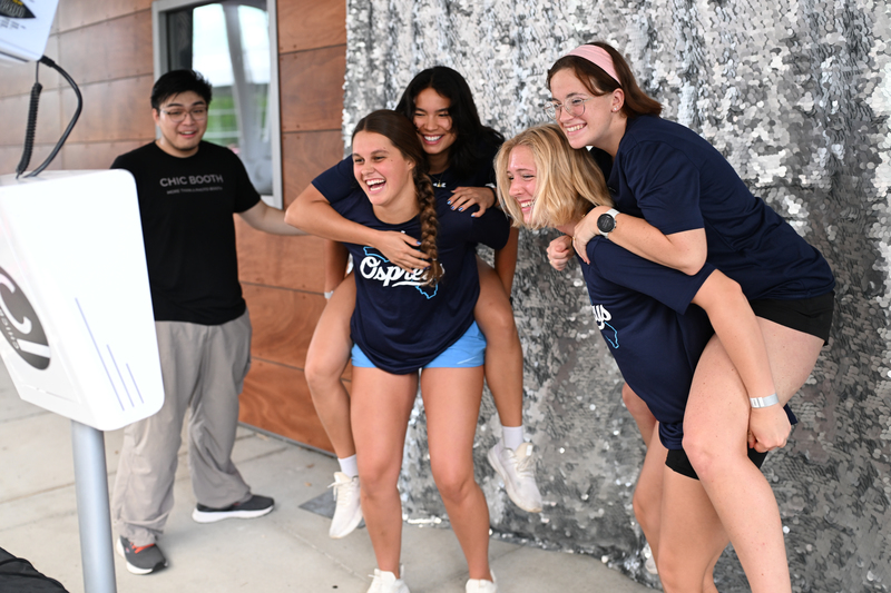 UNF students taking photos while jumping on each others backs