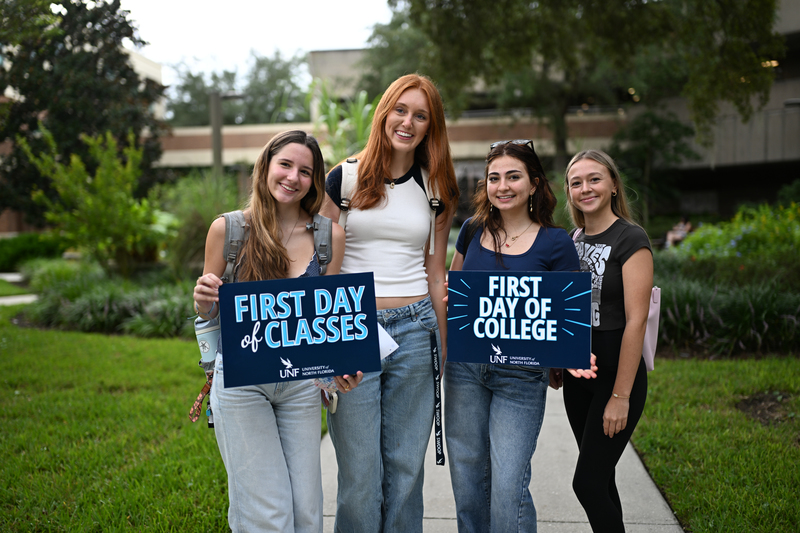 Female UNF students holding signs on the first day of class