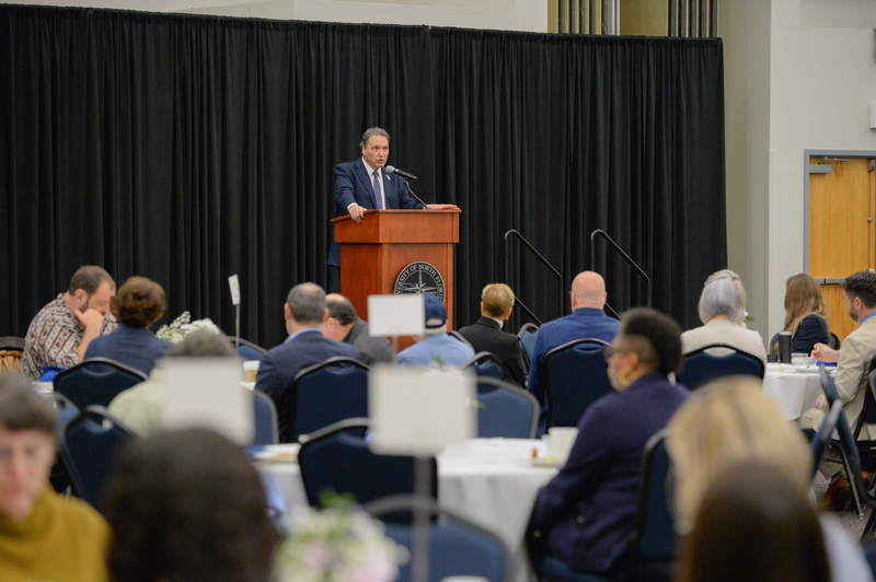 UNF President Moez Limayem at a podium speaking to an audience
