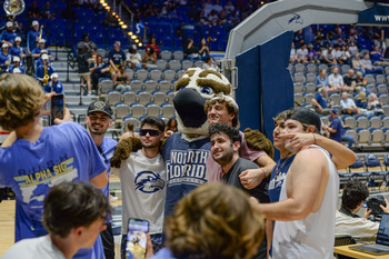 UNF students posing with Ozzie the mascot at a basketball game