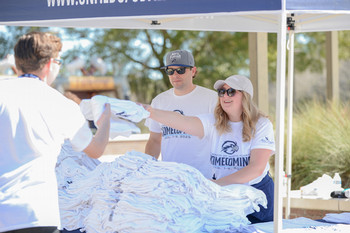 Volunteers at UNF homecoming event passing out t-shirts