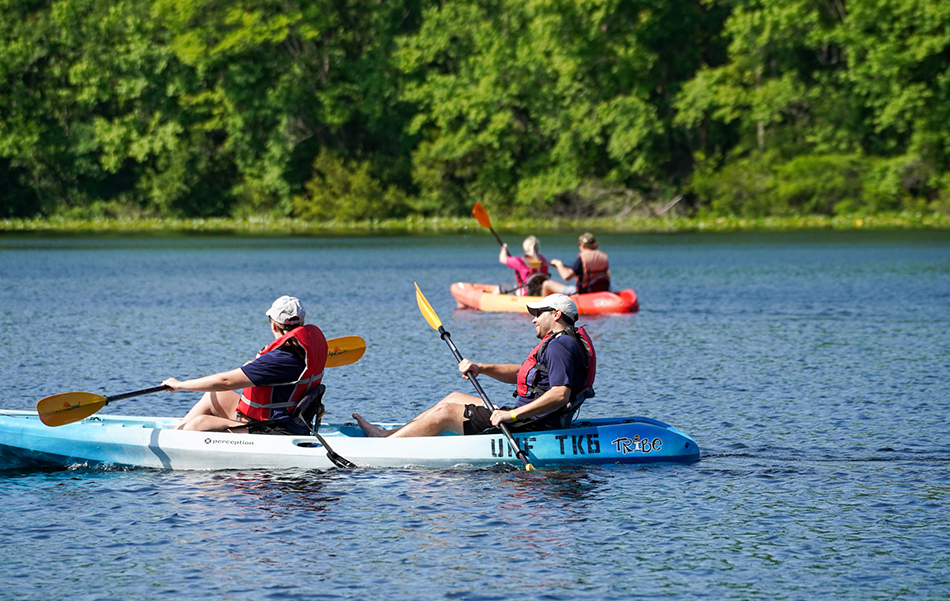Two couples rowing in separate canoes on a lake