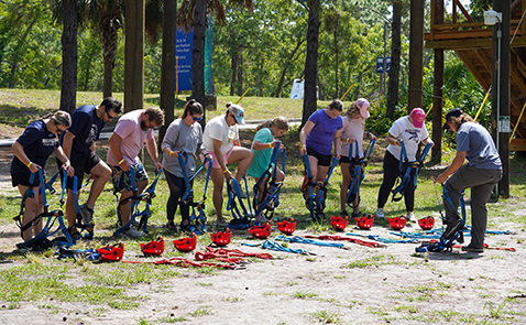 Group of individuals putting on zip line equipment