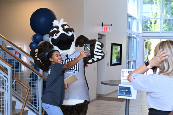 UNF student taking a photo with Ozzie the Mascot