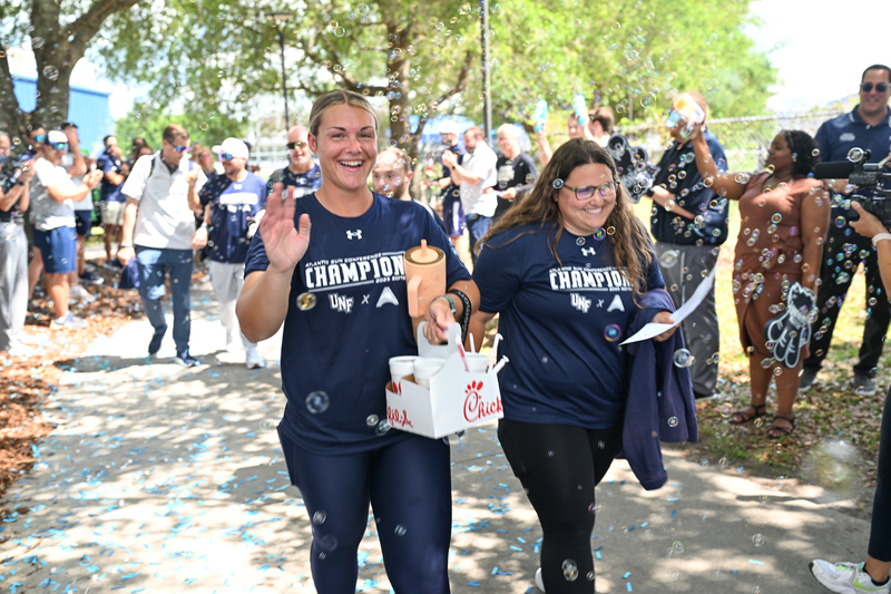 Softball players waving to a crowd