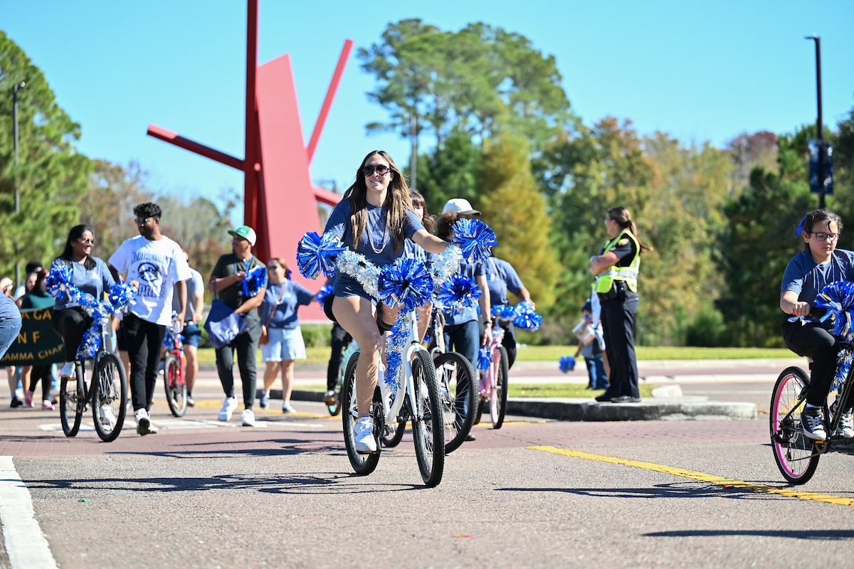 UNF student riding a bike in the Homecoming Parade