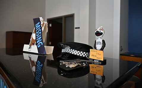 Ozzie the Mascot figurine and police hat on a desk