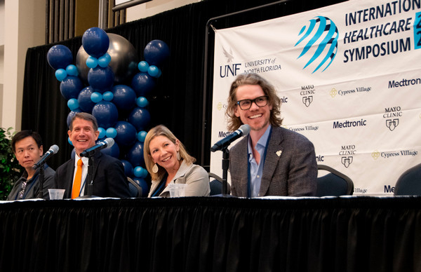Panel of speakers on stage at a healthcare symposium