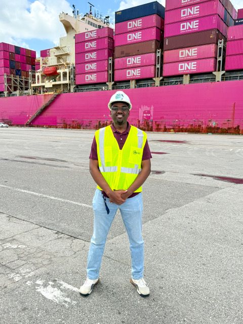 Cameron Myers standing in a shipyard wearing a hard hat and vest