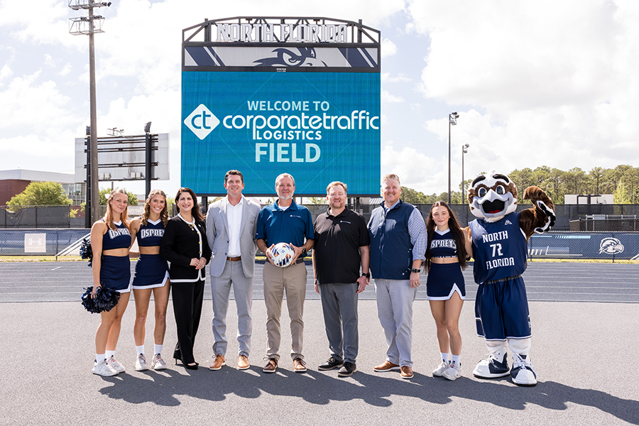 Corporate Traffic Logistics reps and UNF leadership in front of a sign