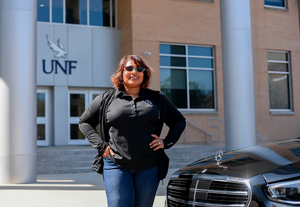 UNF student Sayyada Harry standing in front of a BMW car