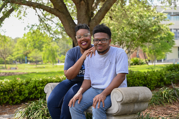 Janelle and Julian Hooks posing on a bench on the UNF campus