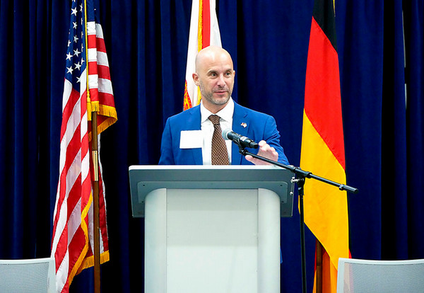 Speaker at a podium with Germany and U.S. flags in the background