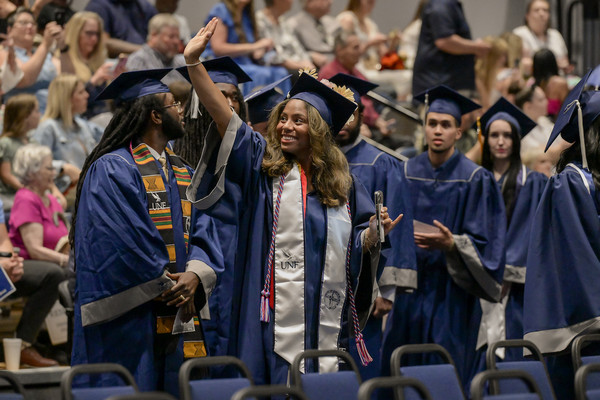 A female UNF students at graduation waving to the audience