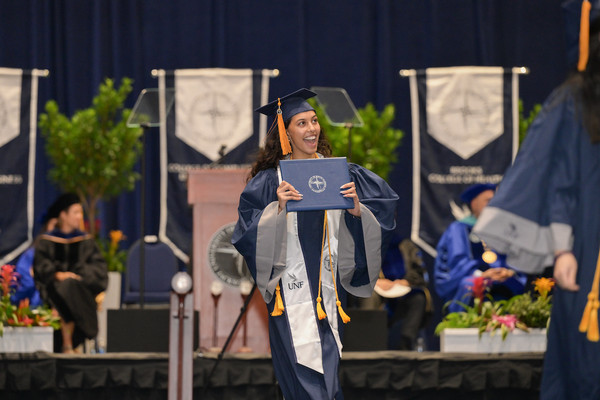 UNF student at graduation walking down the aisle with her diploma