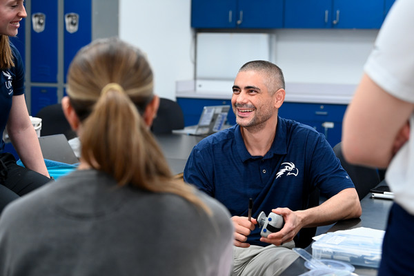 UNF professor Gui Cesar smiling while talking with colleagues