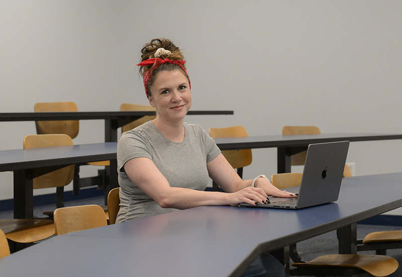 UNF alumna Racquel Rowell sitting in a classroom with a laptop