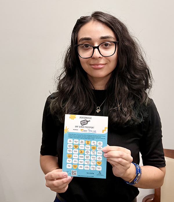 UNF student holding a UNF Diner Passport card