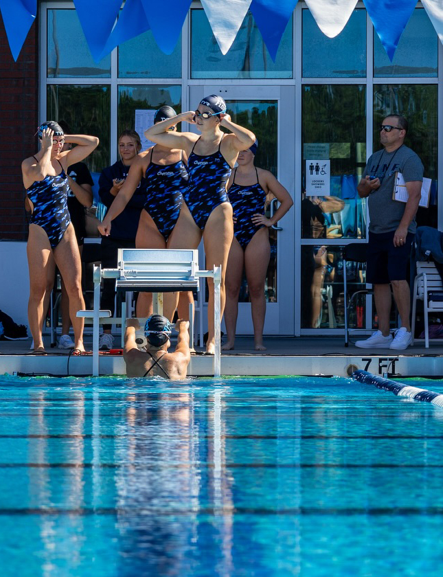 UNF swimmers standing by the pool at a meet