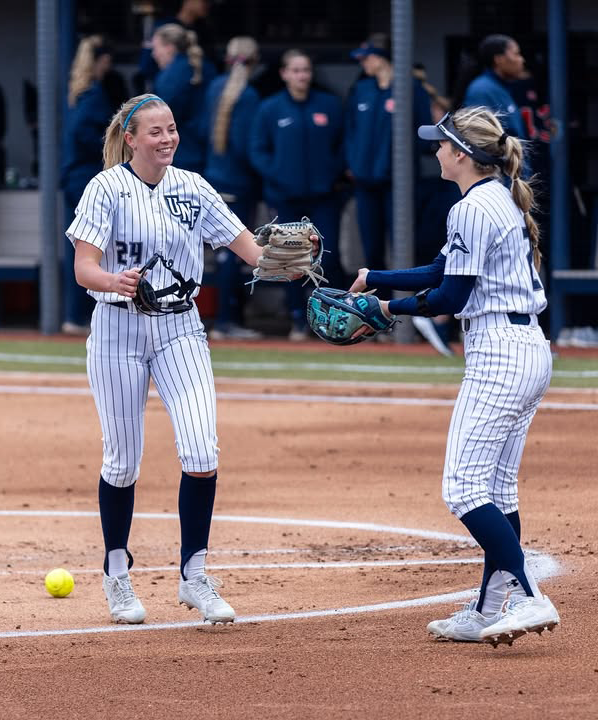 UNF softball players conversing on the field during a game