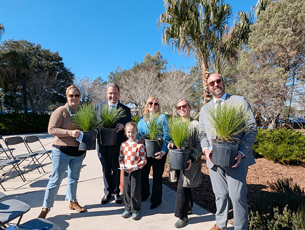 President Moez Limayem standing beside a family holding plants